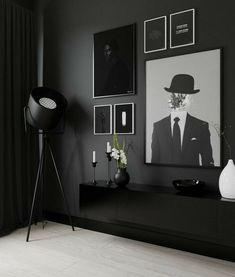 a black and white living room with pictures on the wall, vases and lamp