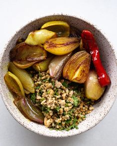 a white bowl filled with vegetables on top of a table next to a red pepper