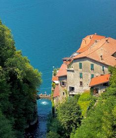 an old house on the edge of a cliff overlooking a body of water and trees