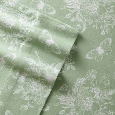 the fabric is green and has white flowers on it, as well as a light blue background