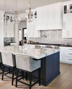 a large kitchen with white cabinets and marble counter tops, along with bar stools