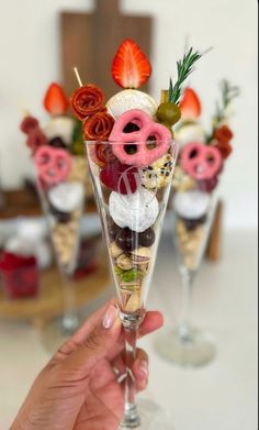 a person holding up a wine glass filled with desserts and strawberries in it