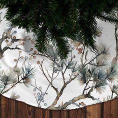 a white table cloth with pine branches and berries on it, hanging from a wooden fence