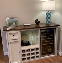 a wine cabinet with many bottles in it and a lamp on the wall behind it