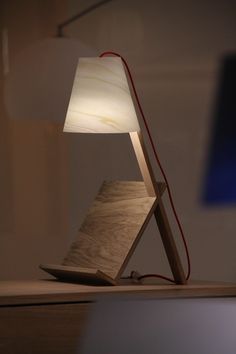 a wooden table lamp with a white shade on it's base and a red cord