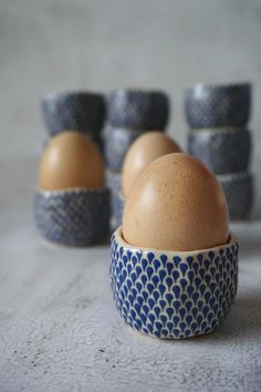 an egg is in a blue and white bowl next to other eggs on a table