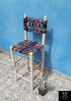 a wooden chair sitting in front of a blue wall next to a potted plant