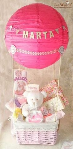 a pink hot air balloon sitting on top of a basket filled with stuffed animals and other items