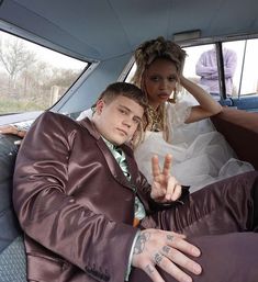 a bride and groom sitting in the back seat of a car with their hands up