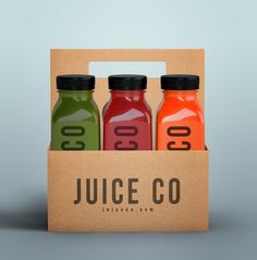 three juice bottles in a cardboard box with the word juice co printed on one side