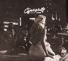 a black and white photo of a woman sitting in front of a sign that reads chicago