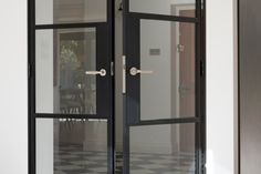 an open glass door in the middle of a room with black and white checkered flooring