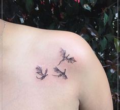 the back of a woman's shoulder with three small dragon tattoos on it