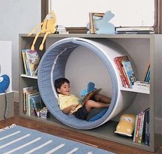 a young boy is sitting in a circular shaped chair with books on the floor and reading