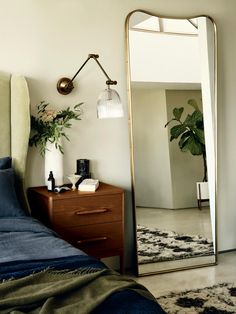 a bedroom with a bed, mirror and plant