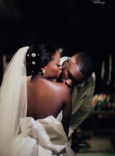 a bride and groom kissing in the dark