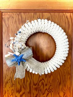 a white wreath with blue ribbon hanging on a wooden door