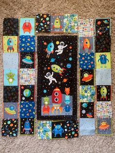 a patchwork wall hanging made out of various space related items, including rockets and aliens