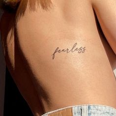 a woman's back with the word fearless tattooed on her left side ribcage