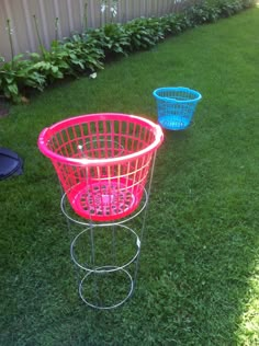 two blue and pink baskets sitting on top of a grass covered field next to a fence