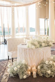 a table with flowers and candles on it in the middle of a room filled with chairs