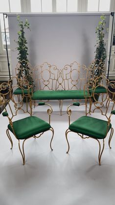 a set of four chairs and a table with green cushions in front of a white wall