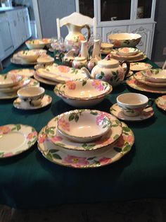 a green table topped with lots of plates and bowls