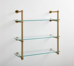 three glass shelves with brass fixtures on each shelf