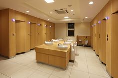 an empty bathroom with several sinks and urinals on the wall, in front of wooden cabinets