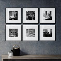 four black and white photographs hang on the wall above a table with a watering can