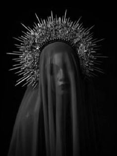 black and white photograph of the face of mary with spikes on her head in front of a dark background