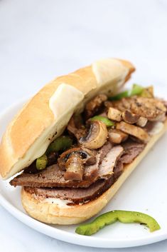 a sandwich with meat, mushrooms and peppers on a plate