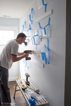 a man working on a wall with blue adhesive tape and tools in his hands