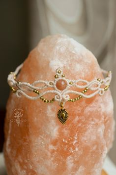 a white and gold beaded head piece on top of a rock