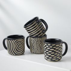 four black and white coffee mugs stacked on top of each other in front of a white background