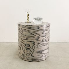 a vase sitting on top of a white floor next to a glass bottle with a cork sticking out of it