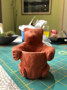 a clay bear sitting in a pot on a table