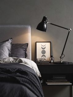 a bedroom with a bed, lamp and pictures on the side table in front of it