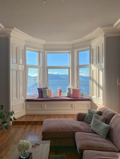 a living room filled with furniture next to a large window covered in lots of windows