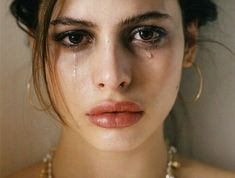 a woman with tears on her face and necklace