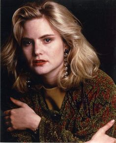 a woman with blonde hair and earrings posing for a photo