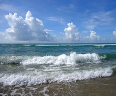 the waves are coming in to shore on a sunny day with blue sky and white clouds