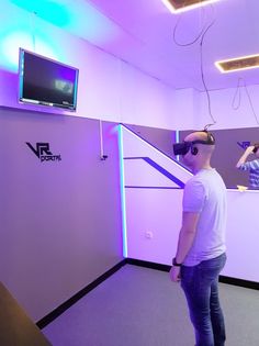 two people wearing virtual headsets standing in front of a wall with a tv on it