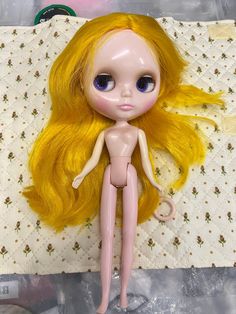 a doll with blonde hair laying on a bed