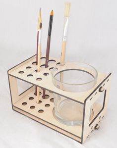 a cup holder with four brushes and two empty bowls on the bottom one is made out of plywood