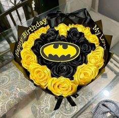 a birthday cake decorated with yellow roses and a batman logo on it's top