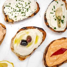 four pieces of bread with different types of food on them and one has an olive in the middle