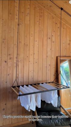 a room with wood paneling and a mirror hanging from the ceiling, along with clothes on a rail