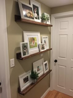 three wooden shelves with pictures on them in front of a white door and some framed photos