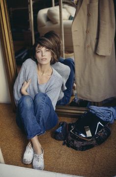 a woman sitting on the floor in front of a mirror